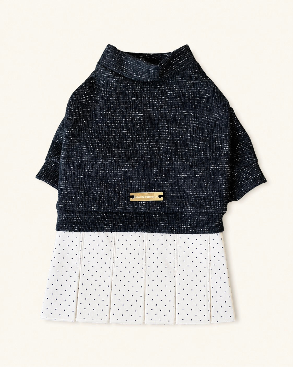 A short-sleeve pet sweater dress featuring a dark black knit top and a white pleated skirt with small black polka dots, accented by a gold-tone metal nameplate on the back.
