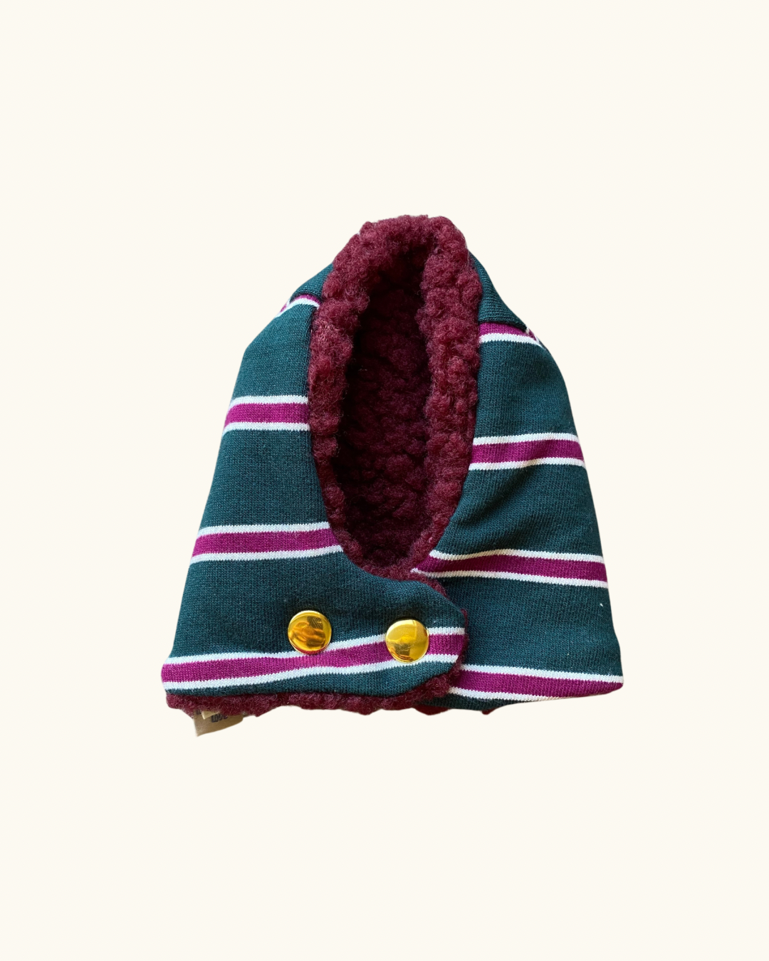 A small striped knit hooded scarf or pet wrap with a plush burgundy fleece lining and two gold buttons, shown on a plain cream background.